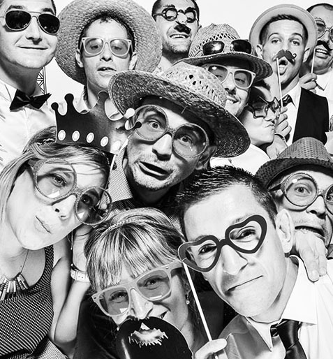 Group of people wearing fun hats, glasses, and props in a photo booth