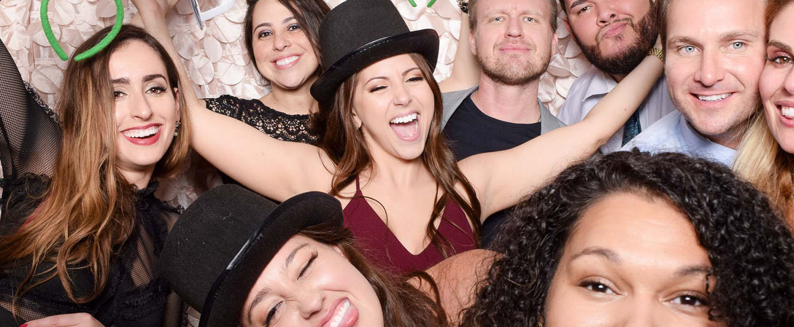 Group of friends posing with silly faces and props in a photo booth, enjoying a fun and lighthearted moment together.